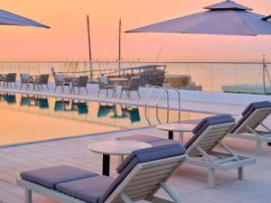 Arabella Beach Hotel Kuwait Vignette Collection, an IHG Hotel في الكويت: مجموعة من الكراسي والطاولات بجانب المسبح