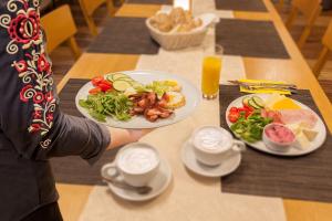 eine Person, die einen Teller Lebensmittel auf einem Tisch hält in der Unterkunft Hotel Lidový dům in Bzenec
