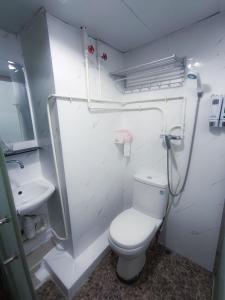 La salle de bains blanche est pourvue de toilettes et d'un lavabo. dans l'établissement Tempo Inn West Kowloon HSR Station, à Hong Kong