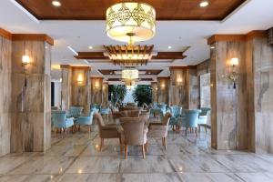 a dining room with tables and chairs and a chandelier at Blue Wave Suite Hotel in Alanya