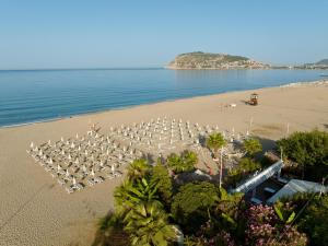 a beach with a bunch of tables and umbrellas at Blue Wave Suite Hotel in Alanya
