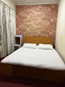 Ce lit se trouve dans une chambre dotée d'un mur en briques. dans l'établissement Sudha’s Garden Home, à Katmandou