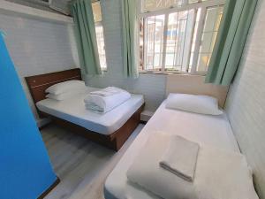 two beds in a small room with two windows at Tempo Inn@ David Mansion in Hong Kong