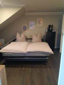 Bett mit weißer Bettwäsche und Kissen in einem Zimmer in der Unterkunft Neumühler Hof - moderne Ferienwohnung "Janica" mit ruhiger Lage zum Garten raus mit kostenfreien Wlan und Netflix in Schwerin