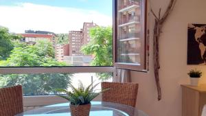 comedor con mesa de cristal y ventana en Mood Bilbao Apartamentos - New & Special, en Bilbao