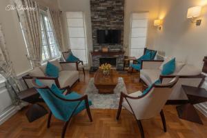 a living room with chairs and a table and a tv at The Tapherini Bungalow in Nuwara Eliya