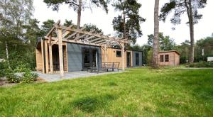 een kleine hut met een bank in een tuin bij Luxe Bos Cottage SERENDIPITY in Beekbergen