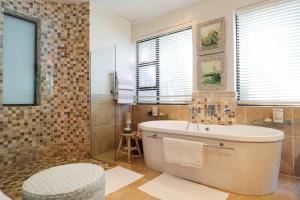 a bathroom with a tub and a shower with windows at Dolphinvilla Seaview apartments 2 Bedrooms in Wilderness