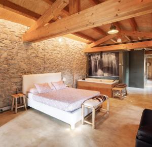 - une chambre avec un lit et un mur en pierre dans l'établissement El Rebastral - Mas Vinyoles Natura, à Sant Pere de Torelló