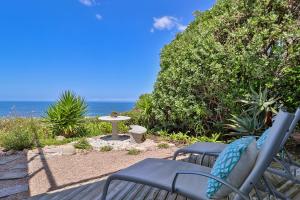 a patio with two chairs and a table and the ocean at Dolphinvilla Seaview apartments 2 Bedrooms in Wilderness