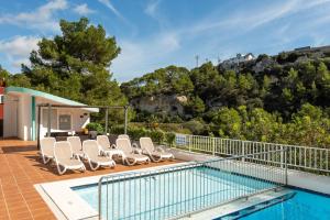 a swimming pool with lounge chairs next to a house at Alta Galdana Playa in Cala Galdana