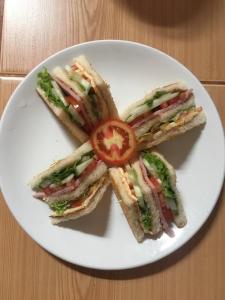 a white plate with a sandwich with a tomato on it at Smile Resort Koh Mook in Ko Mook