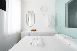 a white bedroom with a white bed and a mirror at VIVO Rooms in Civitanova Marche