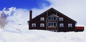 Ein schwarzes Gebäude im Schnee vor einem Berg. in der Unterkunft ACE KITE HOTEL in Çomaklı