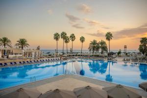 a pool at the beach with palm trees and chairs at Adora Hotel & Resort in Belek