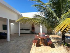a patio with wooden benches and a palm tree at Beachhouse in Barra do Sirinhaém in Barra do Sirinhaém