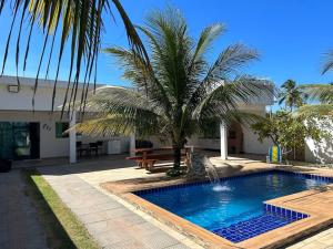 uma piscina com uma palmeira ao lado de um edifício em Beachhouse in Barra do Sirinhaém em Barra do Sirinhaém
