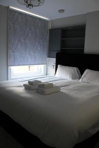 een wit bed met handdoeken en een raam bij MOXIE LUXURY APARTMENTS in Belfast