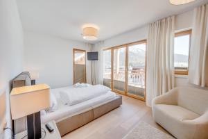 ein Schlafzimmer mit einem Bett, einem Stuhl und einem Fenster in der Unterkunft Luxus Chalet - Zentral - Poolblick mit Sauna in Seefeld in Tirol