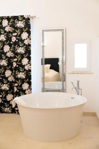 a white bath tub in a bathroom with a mirror at The White Knight Premium Boutique Hotel in Għajnsielem