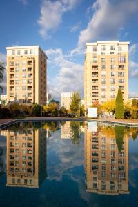 two tall buildings are reflected in a pool of water at Adagio apartment in Creţuleasca