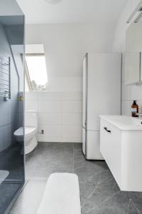 a white bathroom with a toilet and a sink at Newly built westcoast dream home in Ängelholm +25 photos