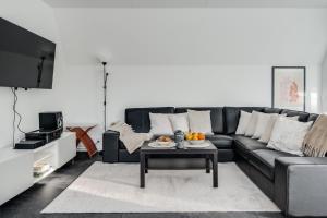 a living room with a black couch and a table at Newly built westcoast dream home in Ängelholm