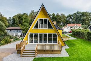 una pequeña casa amarilla con porche y patio en Newly built westcoast dream home en Ängelholm