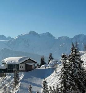 una casa en la cima de una montaña cubierta de nieve en B & B Hôtel Aux Mille Etoiles, en Les Marécottes