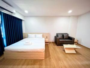 Habitación de hotel con cama y silla en JIA HAUS Hotel Apartment en Buriram