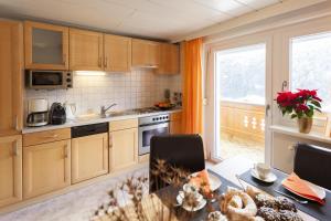 una cucina con armadi in legno, tavolo e finestra di Appartement Zint a Sankt Gallenkirch