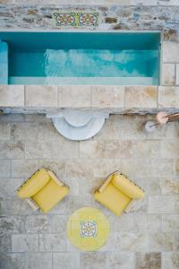 an overhead view of a swimming pool with yellow seats at Aristide Hotel - Small Luxury Hotels of the World in Ermoupoli