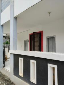 - un bâtiment noir et blanc avec une porte rouge dans l'établissement MyKost Palupuh Valley Syariah, à Bogor