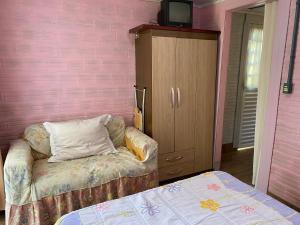ein Schlafzimmer mit einem Sofa und einer rosa Wand in der Unterkunft Mini house Nara in Canela