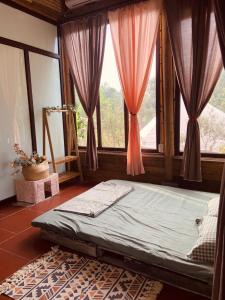 uma cama num quarto com uma grande janela em Nhà Gỗ An Trăm Tuổi - Chill Garden Lakeview em Hanói