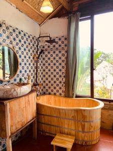 una gran bañera de madera en un baño con ventana en Nhà Gỗ An Trăm Tuổi - Chill Garden Lakeview en Hanoi