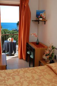 a bedroom with a bed and a desk and a balcony at Hotel Da Fine in Seccheto