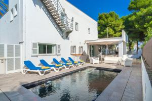 a swimming pool with lounge chairs and a house at Miramar Manresa Alcudia in Alcudia
