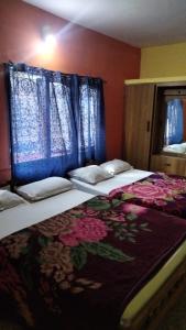a bedroom with two beds with blue curtains at Long Wood Hills Cottage in Ooty