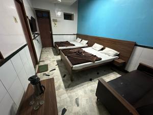 2 camas en una habitación con una pared azul en New Royal Hotel, en Nueva Delhi