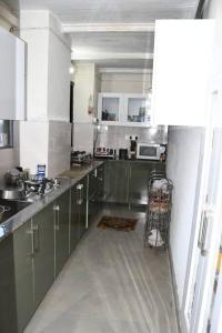 uma cozinha com armários de aço inoxidável e um carrinho dentro em Orchard Oasis Home Stay em Mukteshwar