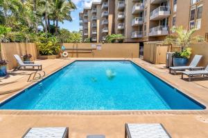 a swimming pool with chairs and a building at Nani Kai Hale A209 in Kihei