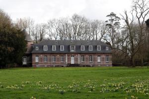 a large brick house in a field with flowers at Le Domaine Saint Ange in Friville-Escarbotin