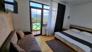 a bedroom with a bed and a couch and a large window at SPA hotel Villa Sofia in Yablunytsya