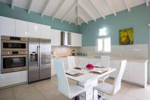 cocina con mesa blanca y sillas blancas en Airport View 3-Bed Villa, en Cupecoy