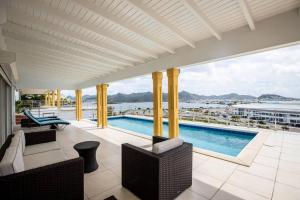 - un balcon avec une piscine et une vue sur l'eau dans l'établissement Airport View 3-Bed Villa, à Cupecoy