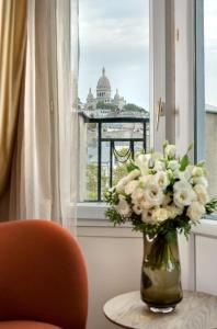 um vaso de flores sentado numa mesa numa janela em Artemisia Montmartre em Paris