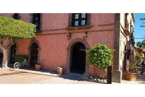 a red building with a door and a bike in front at Hotel Boutique Posada De Las Flores Loreto in Loreto
