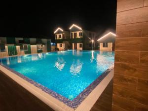 una grande piscina notturna con luci di NEW MOUCHAK HOTEL & RESORTS a Tajpur
