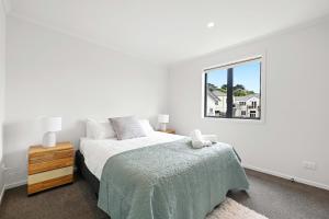 a white bedroom with a bed and a window at New towhouse walk to the hospital & CBD & the Lake in Hamilton